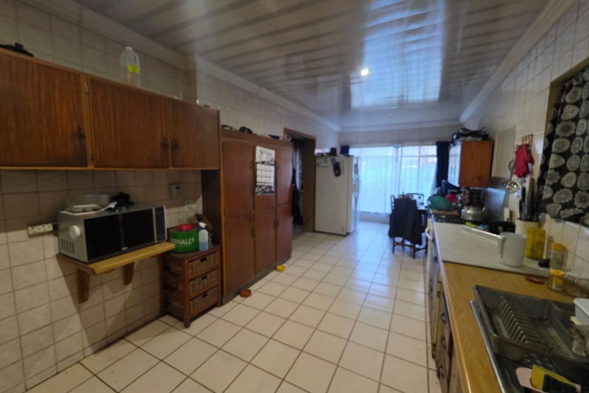 A dated kitchen featuring extensive wooden cabinetry, tiled surfaces, and a functional layout, offering significant potential for a modern renovation.