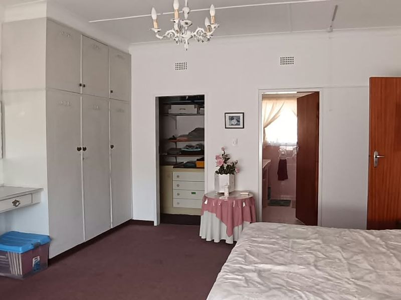 Spacious bedroom featuring extensive built-in cupboard storage, a dedicated vanity area, and direct access to an en-suite bathroom.