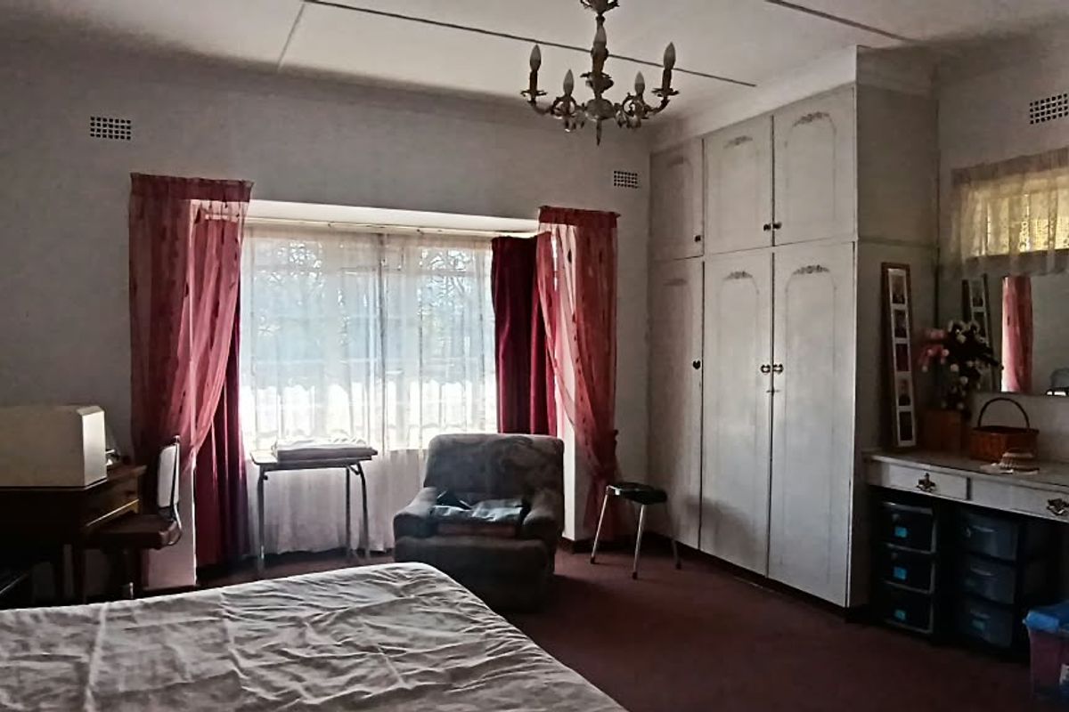 Spacious bedroom featuring extensive built-in cabinetry, a vanity area, and large windows, requiring cosmetic updates to modernize the finishes.