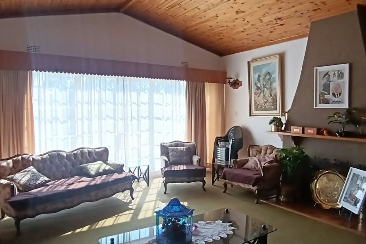 Spacious living room featuring a vaulted timber ceiling, a prominent built-in fireplace, and large sliding glass doors that provide ample natural light.