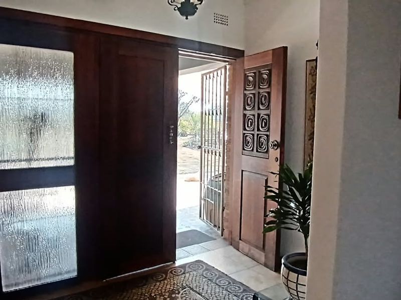 Entrance hall featuring a solid wood front door with textured glass panels and an integrated security gate leading to the exterior.