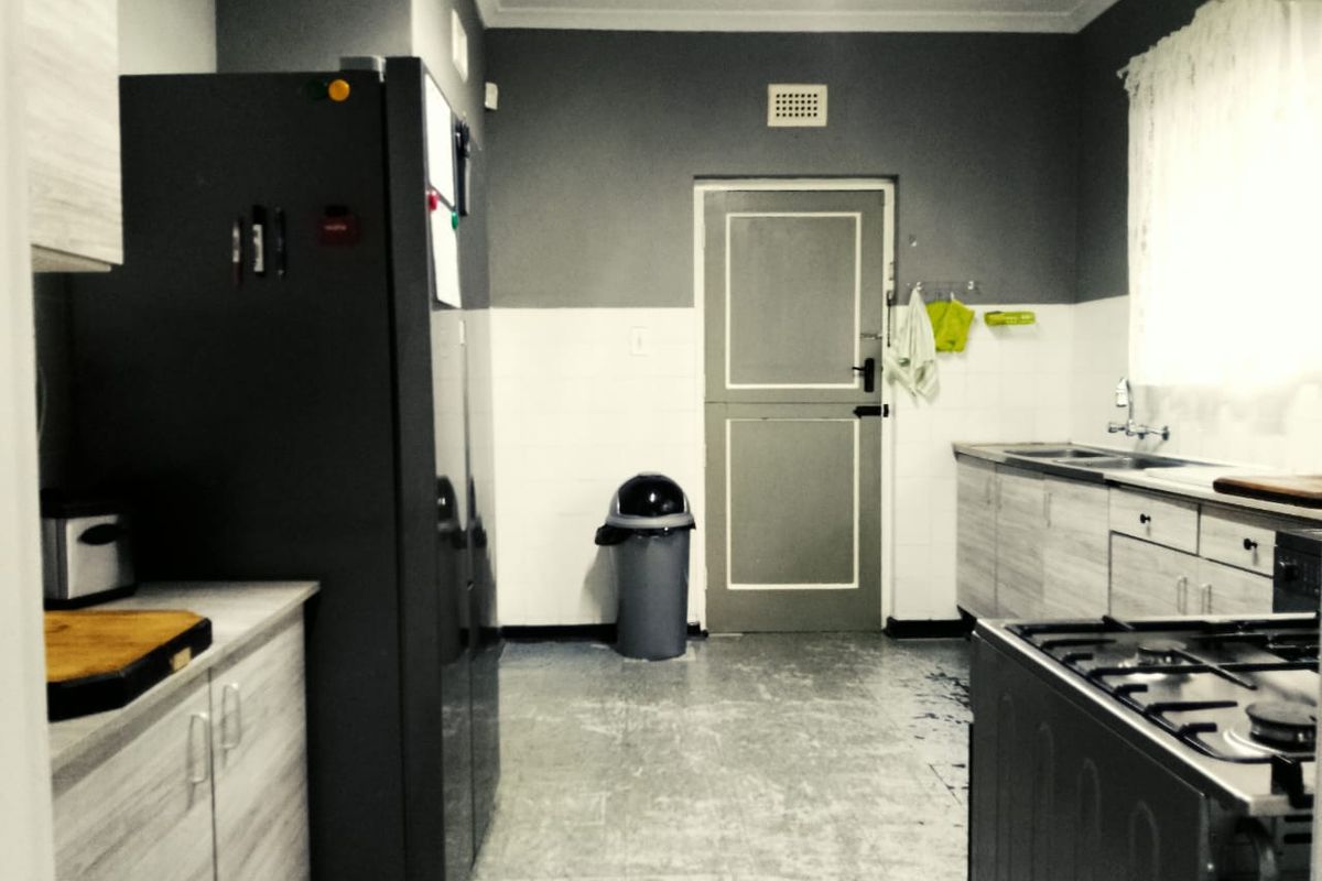 Functional kitchen featuring built-in cabinetry, gas hob, extractor fan, and stainless steel sink with tiled splashback and durable flooring.