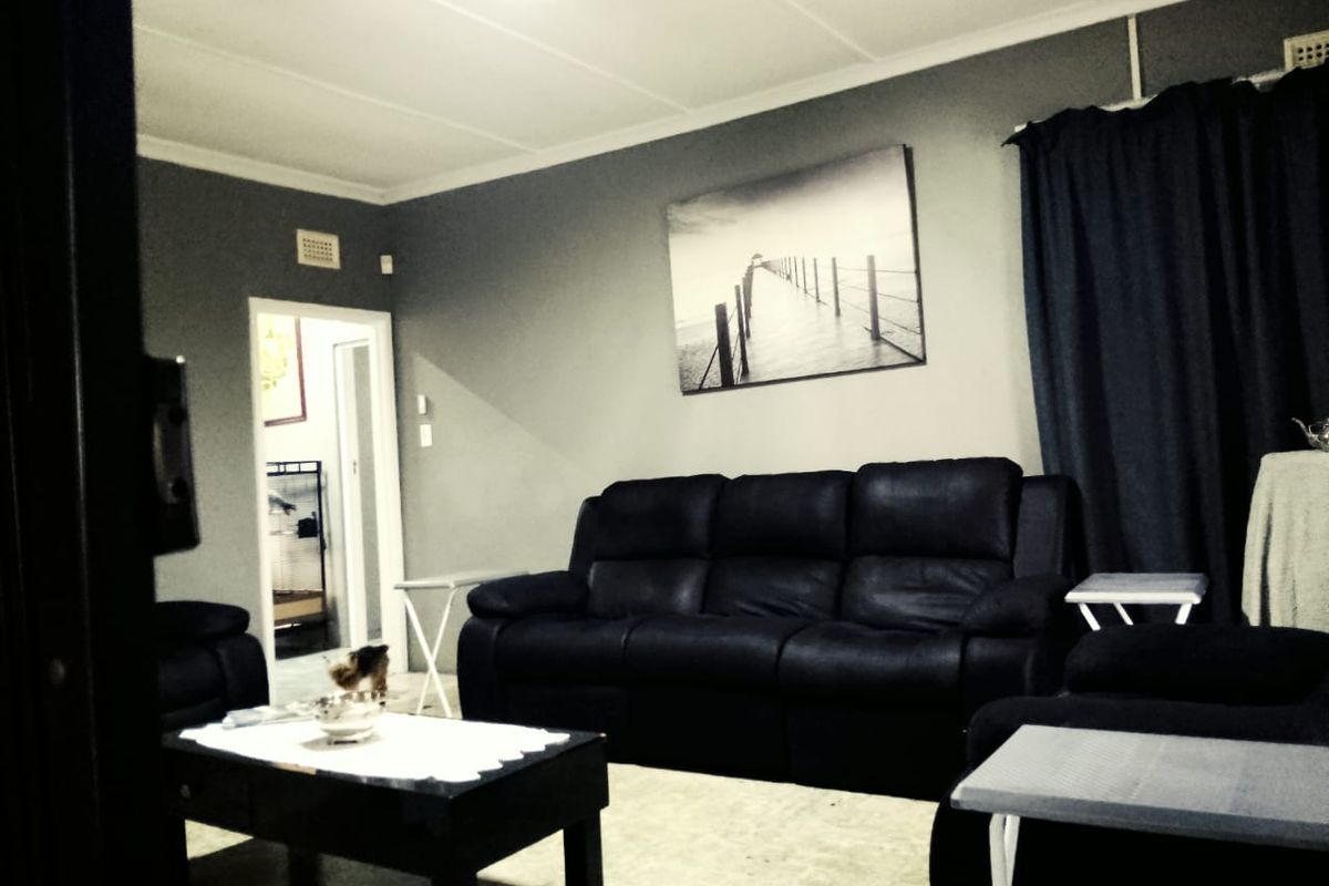 A living room featuring grey walls, coved ceilings, and a doorway leading to an adjacent space.