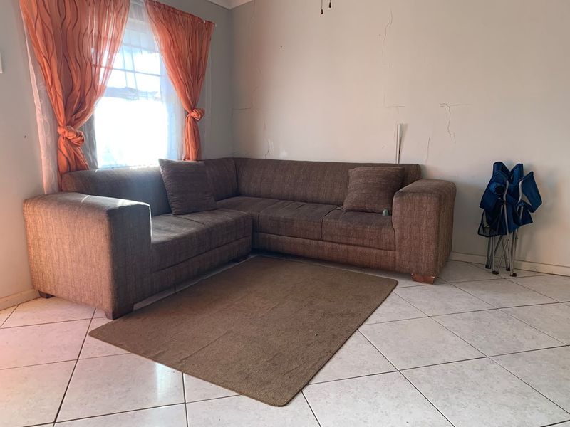 A living room area featuring tiled flooring and a window, showing visible signs of wall plaster cracking requiring maintenance.