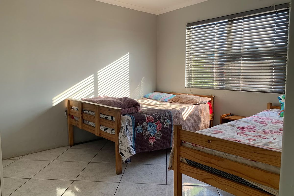 A functional bedroom featuring tiled flooring and venetian blinds, providing a neutral base for potential interior updates.