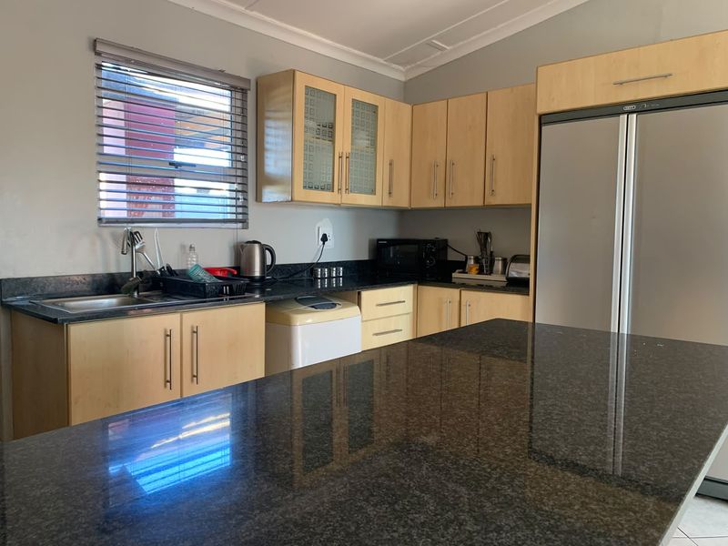 A functional kitchen featuring granite countertops, light wood-finish cabinetry, and a central island, providing ample workspace and storage.