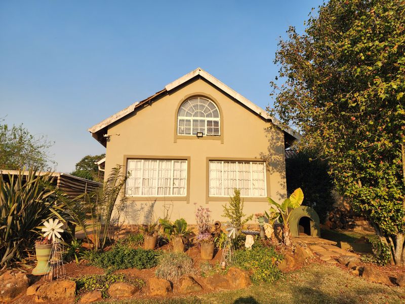 Rear view of a residential house featuring a gabled roof, arched upper window, and landscaped garden area.