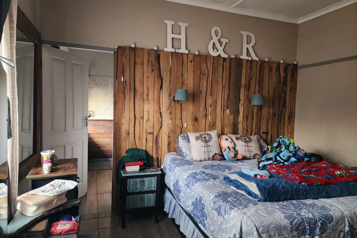 A bedroom featuring a rustic timber feature wall, tiled flooring, and direct access to an adjoining bathroom space.