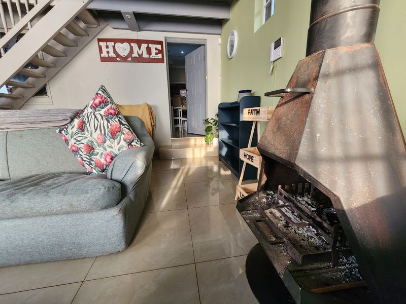 Living room featuring a tiled floor, a prominent freestanding fireplace, and an open staircase leading to the upper level.