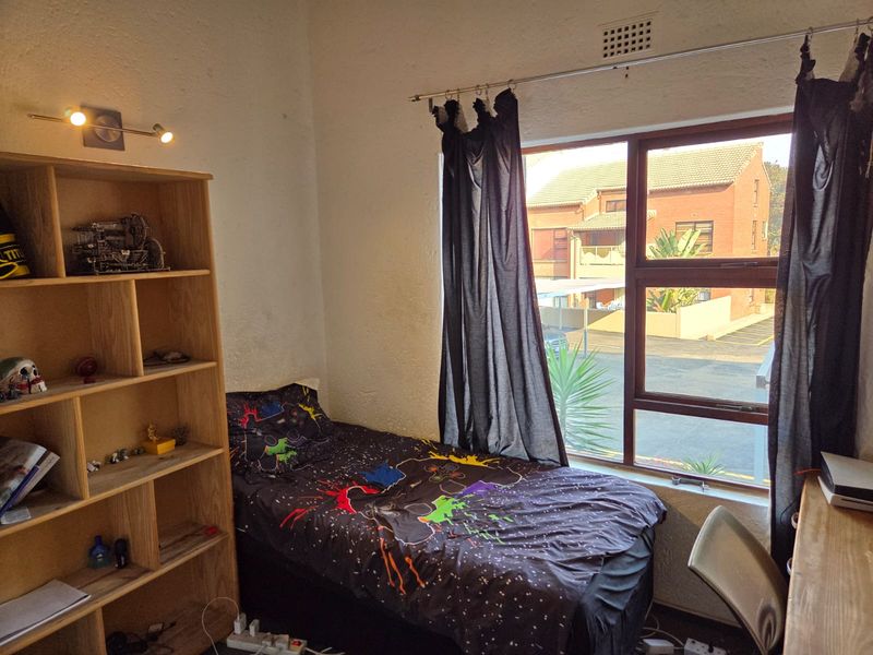 A standard bedroom featuring an aluminium-framed window with natural light and a built-in ventilation grille.