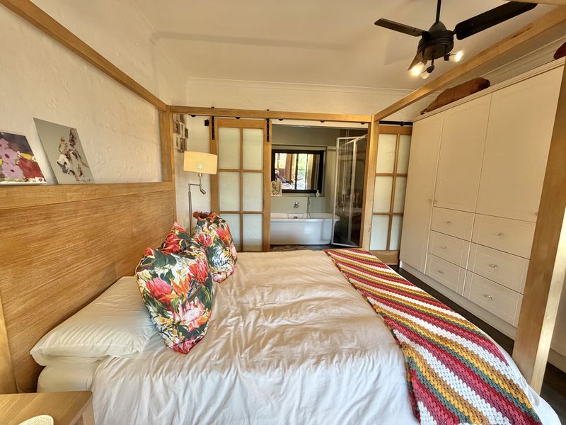 Spacious bedroom featuring a built-in wardrobe, ceiling fan, and sliding barn doors providing direct access to an en-suite bathroom.