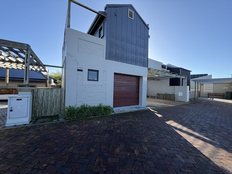 Front exterior view of the property featuring a single garage, timber pergola structure, and paved driveway access.