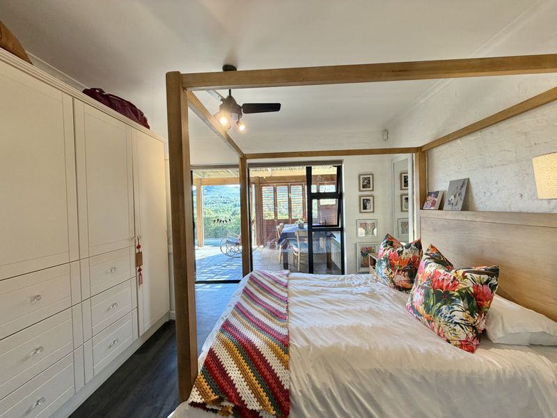 A well-maintained bedroom featuring a built-in wardrobe, ceiling fan, and sliding glass doors that open onto a patio with scenic views.