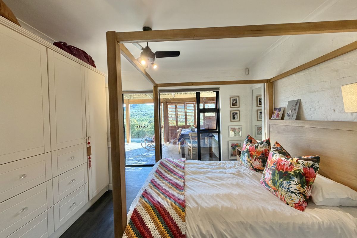 A well-maintained bedroom featuring a built-in wardrobe, ceiling fan, and sliding glass doors that open onto a patio with scenic views.