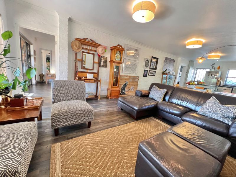 Spacious open-plan living area featuring durable laminate flooring, exposed brick walls, and integrated lighting, creating a warm and inviting atmosphere.