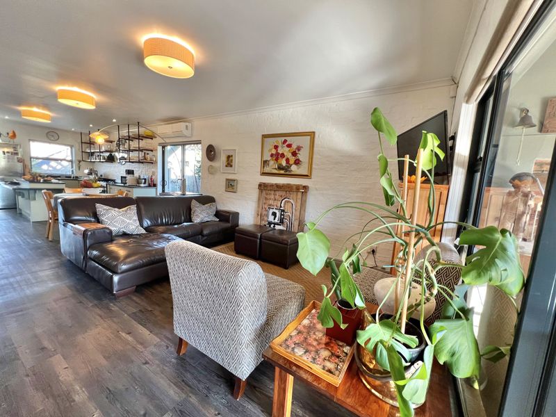 Spacious open-plan living and kitchen area featuring modern laminate flooring, recessed lighting, and a functional kitchen island with integrated cabinetry.