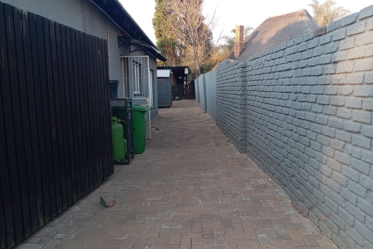 A paved side walkway featuring a brick boundary wall and timber fencing, providing access along the side of the property.
