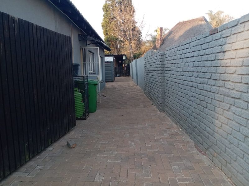 A paved side walkway featuring a brick boundary wall and timber fencing, providing access along the side of the property.