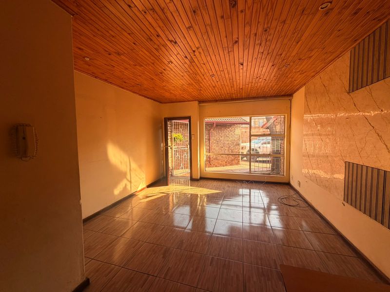Spacious living area featuring a warm timber tongue and groove ceiling, ceramic tiled flooring, and a decorative marble-effect feature wall.