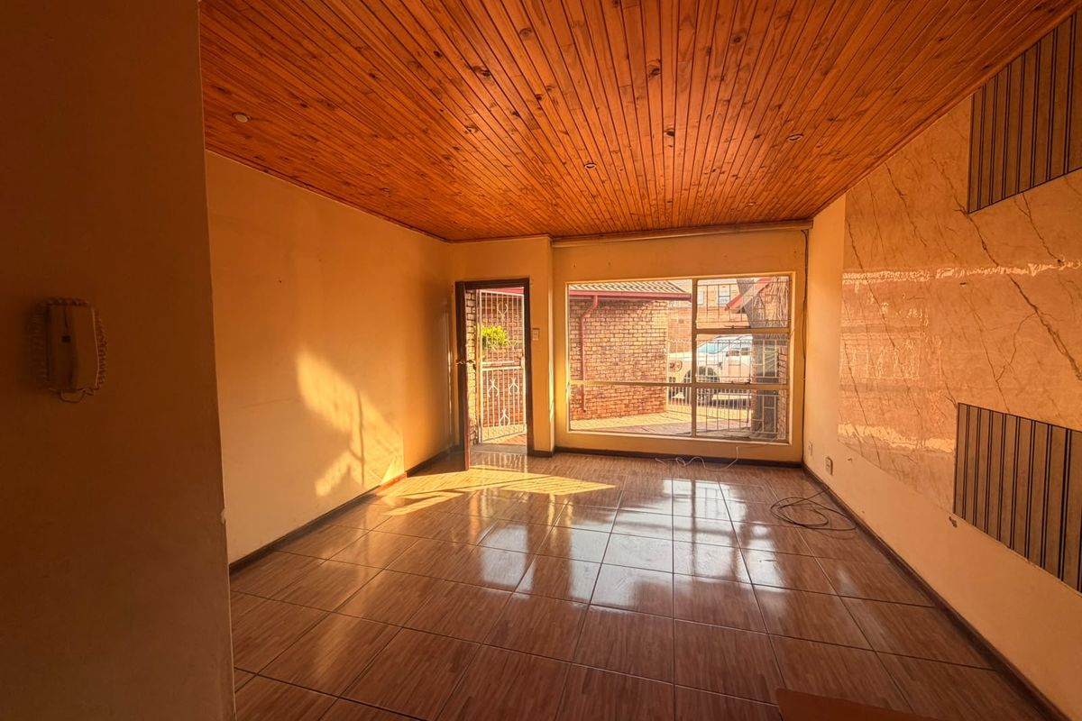 Spacious living area featuring a warm timber tongue and groove ceiling, ceramic tiled flooring, and a decorative marble-effect feature wall.