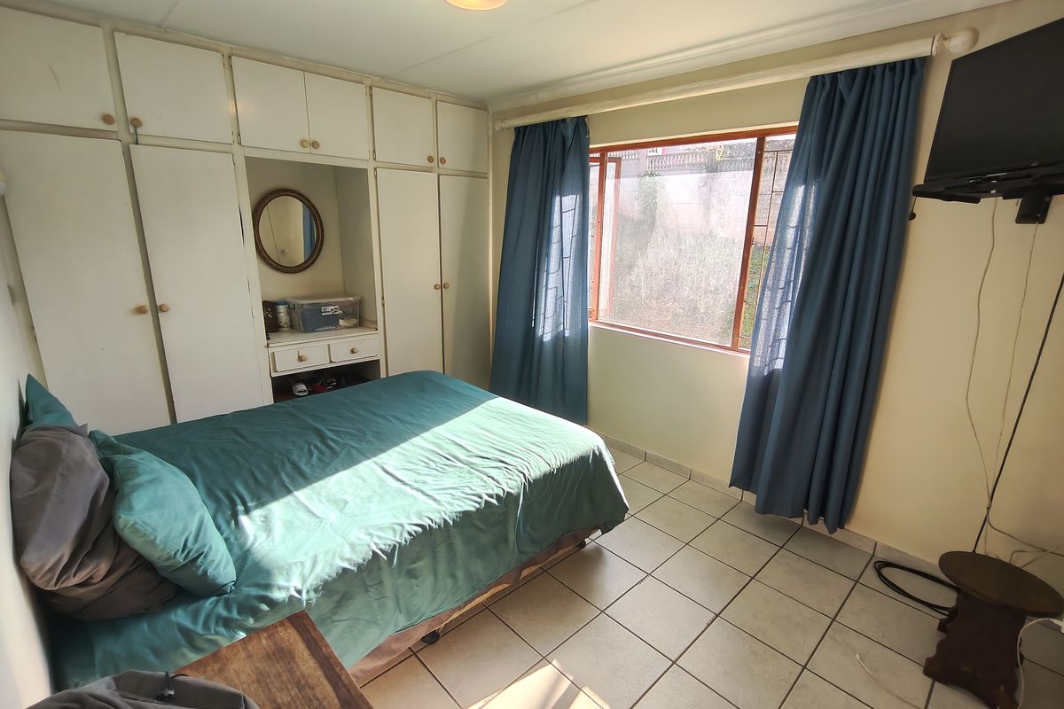 A bedroom featuring built-in cupboards, tiled flooring, and a window with natural light.