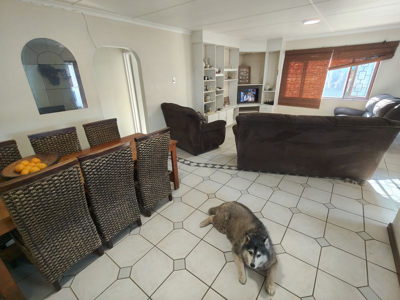 Open-plan living and dining area featuring tiled flooring, a built-in shelving unit, and an arched doorway leading to adjacent spaces.