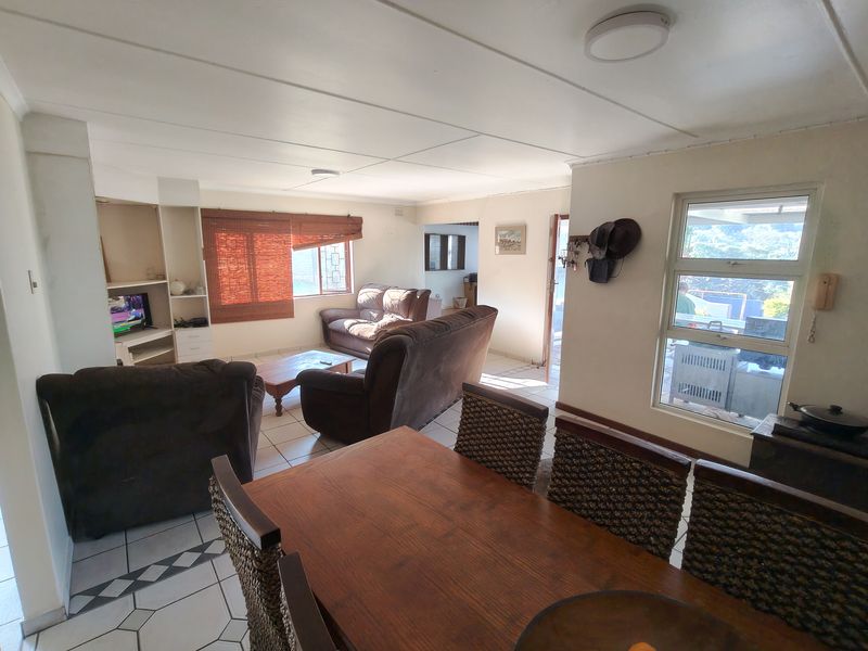 Open-plan living and dining area featuring tiled flooring, built-in shelving, and large windows providing natural light.