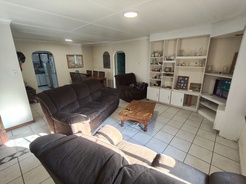 Spacious living room featuring ceramic floor tiles, a large built-in shelving unit, and arched doorways leading to adjacent living areas.