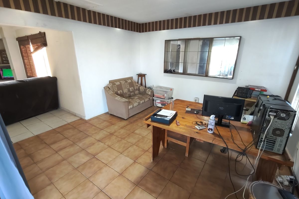 A living area featuring tiled flooring and a decorative wall border, offering a functional space with potential for modernization.