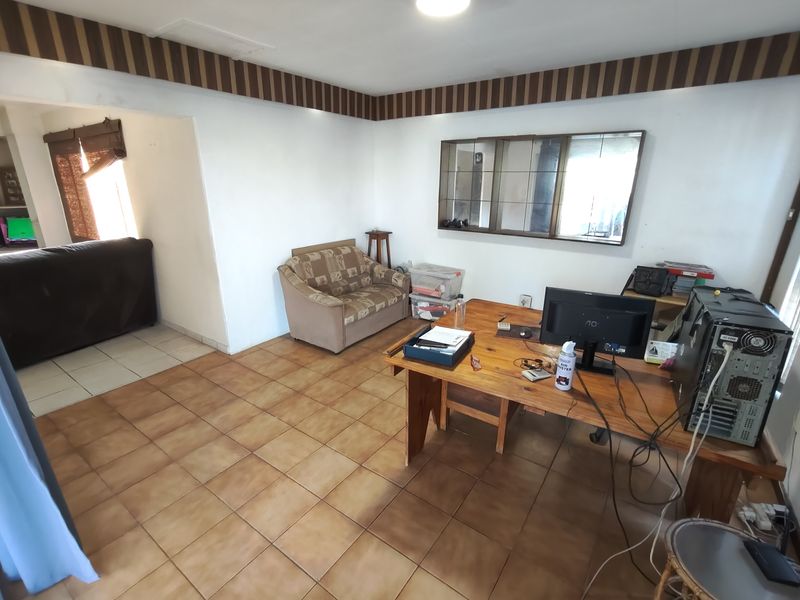 A living area featuring tiled flooring and a decorative wall border, offering a functional space with potential for modernization.