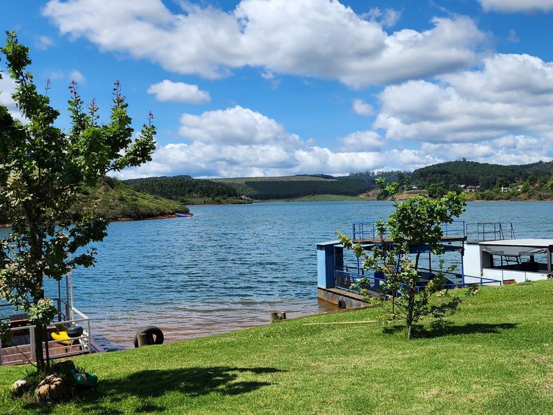 Scenic waterfront view featuring a private jetty and well-maintained lawn, offering direct access to the dam and surrounding landscape.