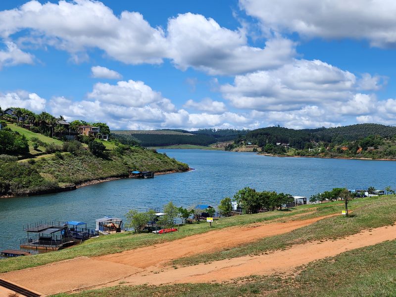 Scenic view of the lake featuring waterfront access and private jetties, showcasing the natural landscape and surrounding residential estate.