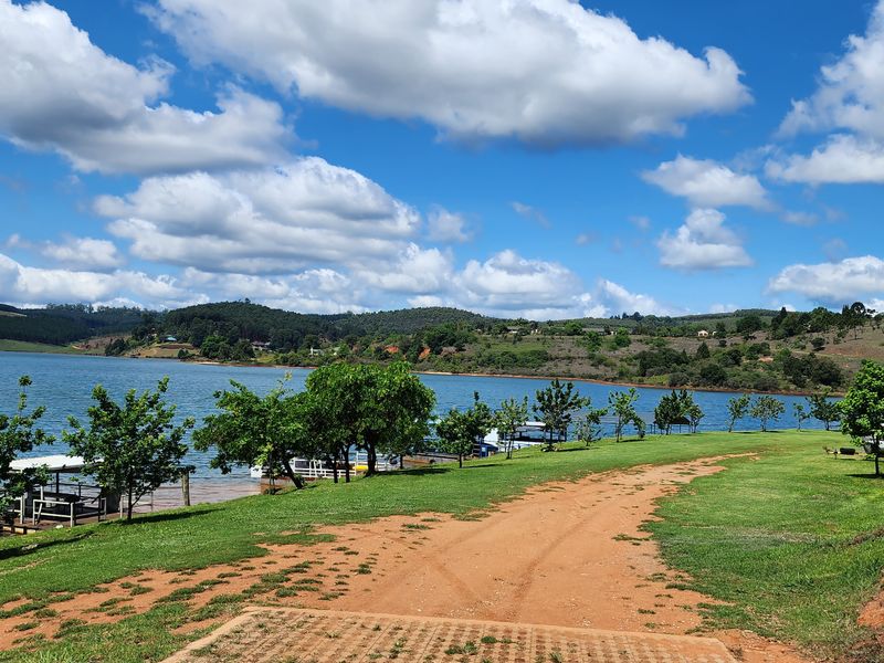 Scenic view of the waterfront property featuring a grassed lawn, dirt access track, and direct access to the lake.