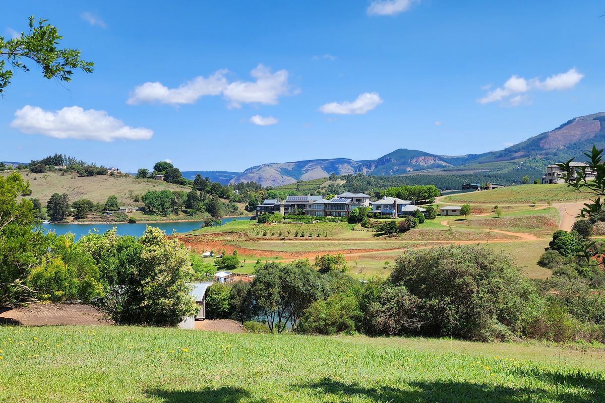 A scenic landscape view overlooking a lake, rolling hills, and distant mountains, showcasing the natural beauty of the surrounding residential estate.