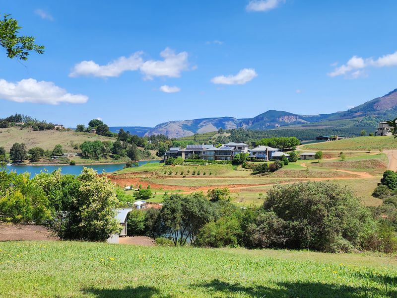 A scenic landscape view overlooking a lake, rolling hills, and distant mountains, showcasing the natural beauty of the surrounding residential estate.