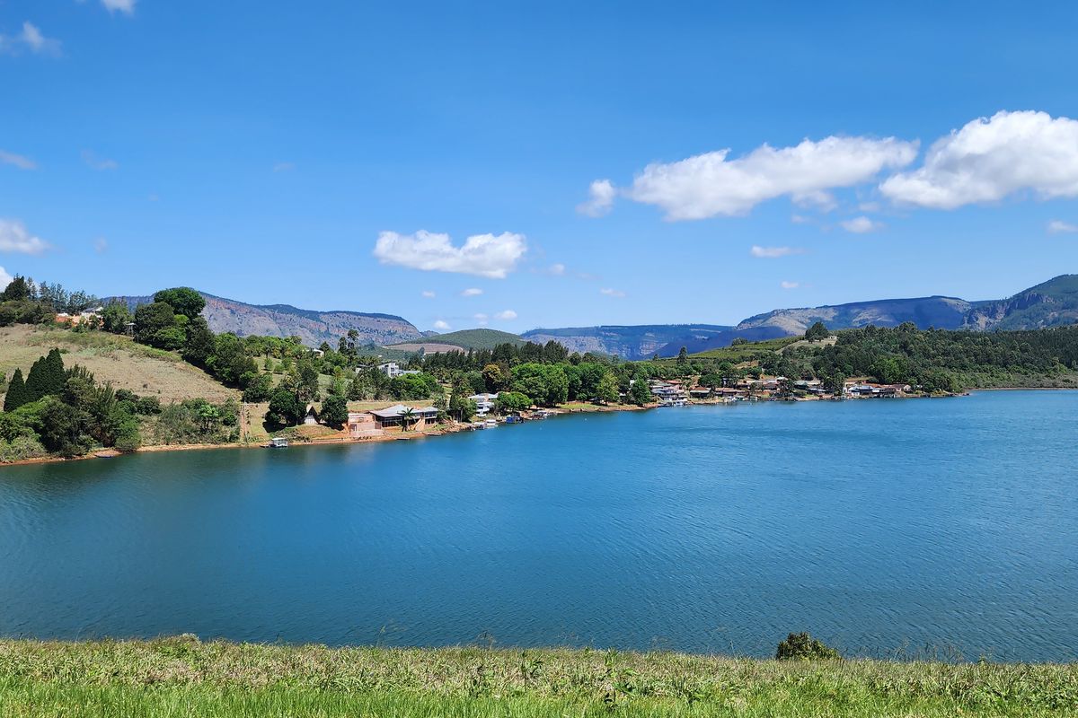 A scenic landscape view overlooking a large lake with surrounding hills and mountains in the distance.