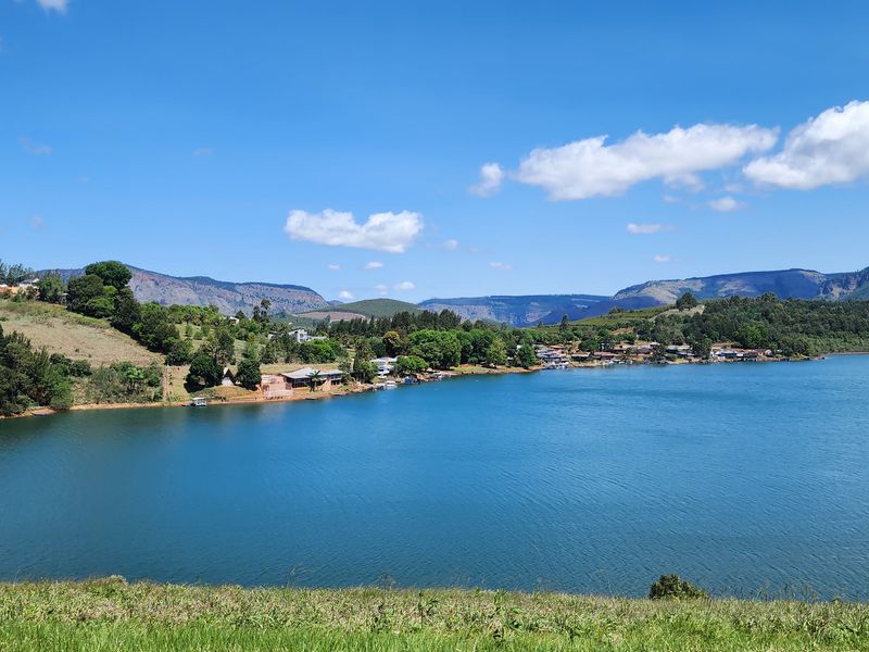 A scenic landscape view overlooking a large lake with surrounding hills and mountains in the distance.
