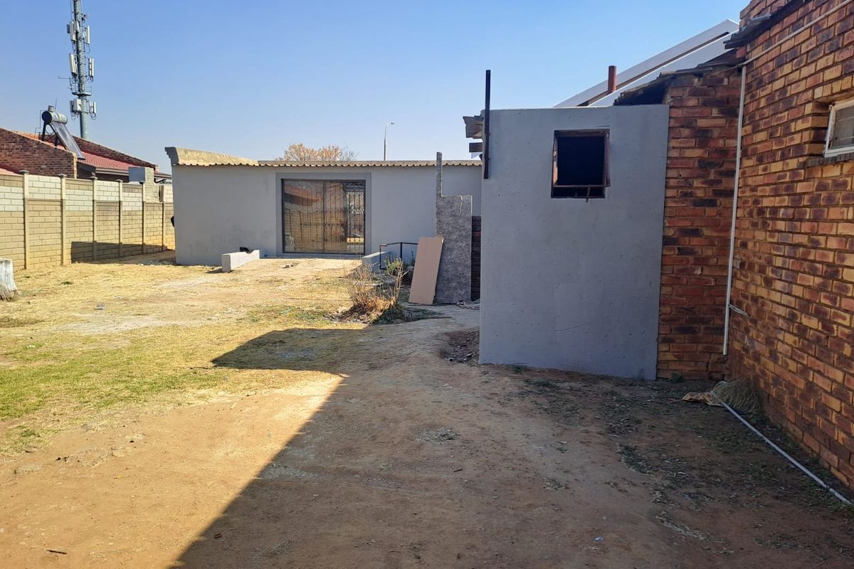 Rear yard area featuring unfinished brick and rendered structures, providing a blank canvas for landscaping and outdoor improvement projects.