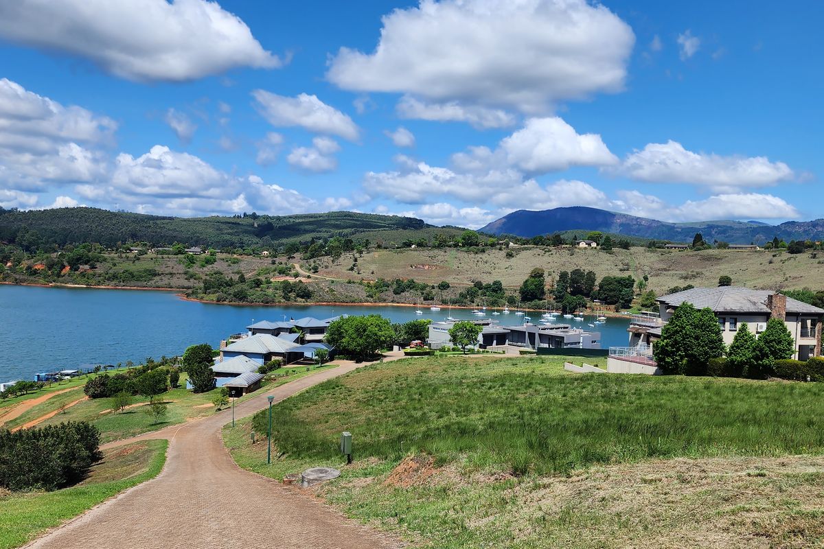 A scenic elevated view overlooking a tranquil lake, surrounding hills, and established residential estate properties.
