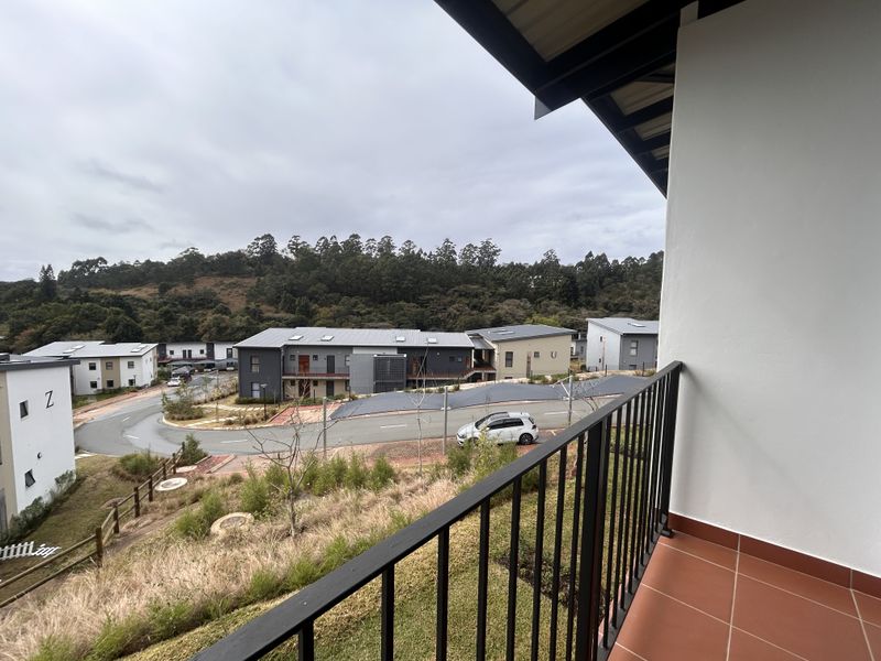A private balcony featuring tiled flooring and a metal balustrade, offering elevated views of the surrounding residential estate and landscape.
