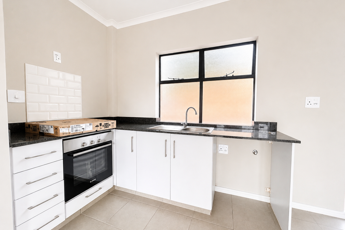 A clean, modern kitchen featuring white cabinetry, granite countertops, a built-in oven, and a subway tile backsplash with neutral floor tiling.