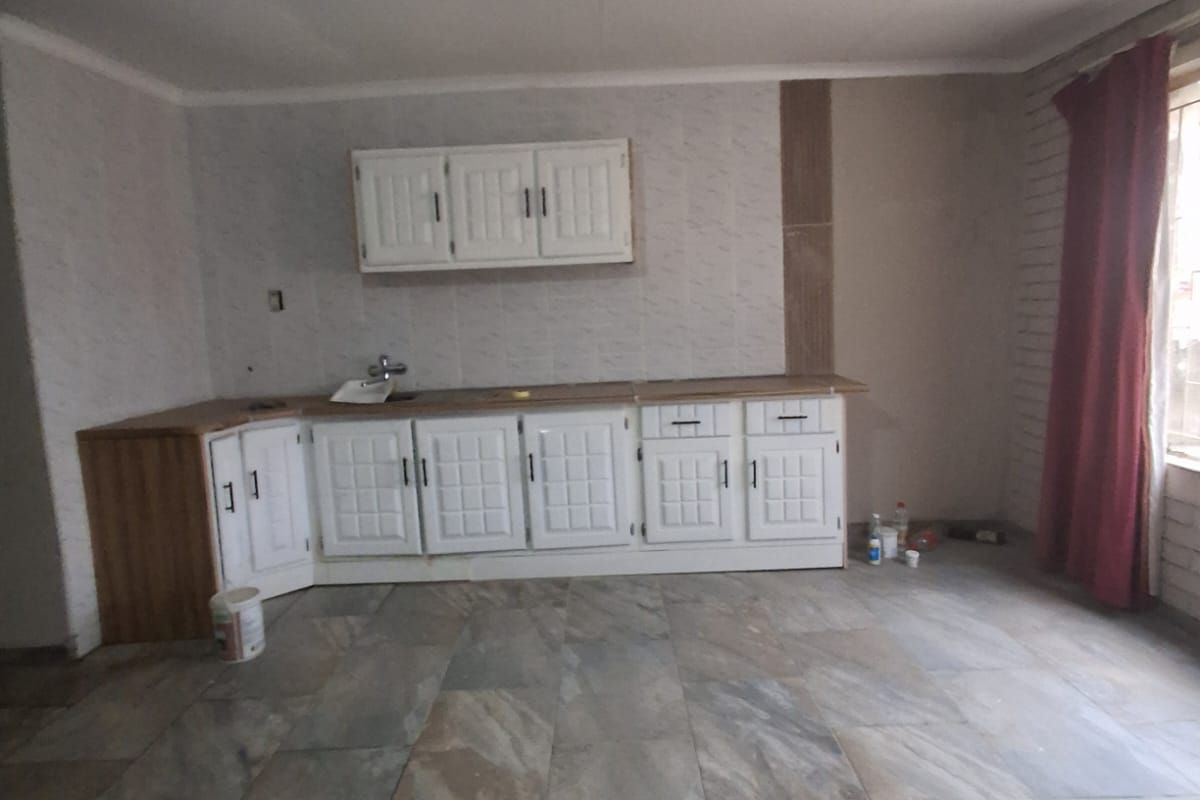 A kitchen area featuring built-in cabinetry, a sink, and tiled flooring, currently in an unfinished state requiring further renovation and completion.