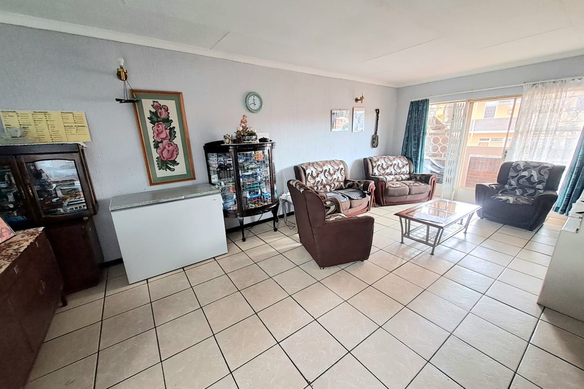 A spacious living room featuring neutral ceramic floor tiles and a large sliding glass door providing natural light and access to the exterior.