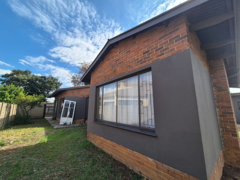 Rear view of the house featuring a combination of exposed brick and painted plaster finishes with aluminium window frames and security bars.