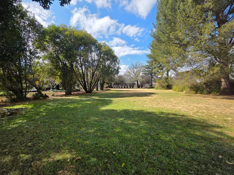 A spacious, well-established garden area featuring mature trees and expansive lawn space, offering a peaceful outdoor setting on the small holding.