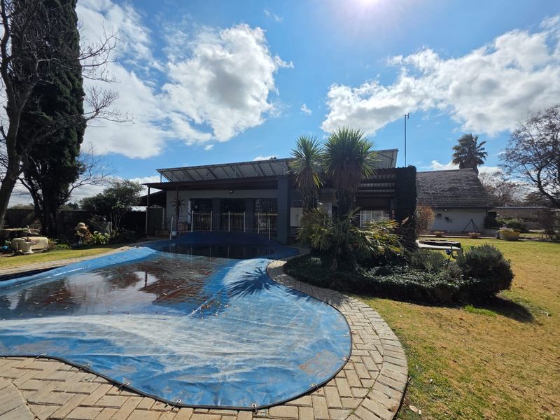 Outdoor pool area featuring a paved surround, covered patio, and solar panel installation on the roof structure.