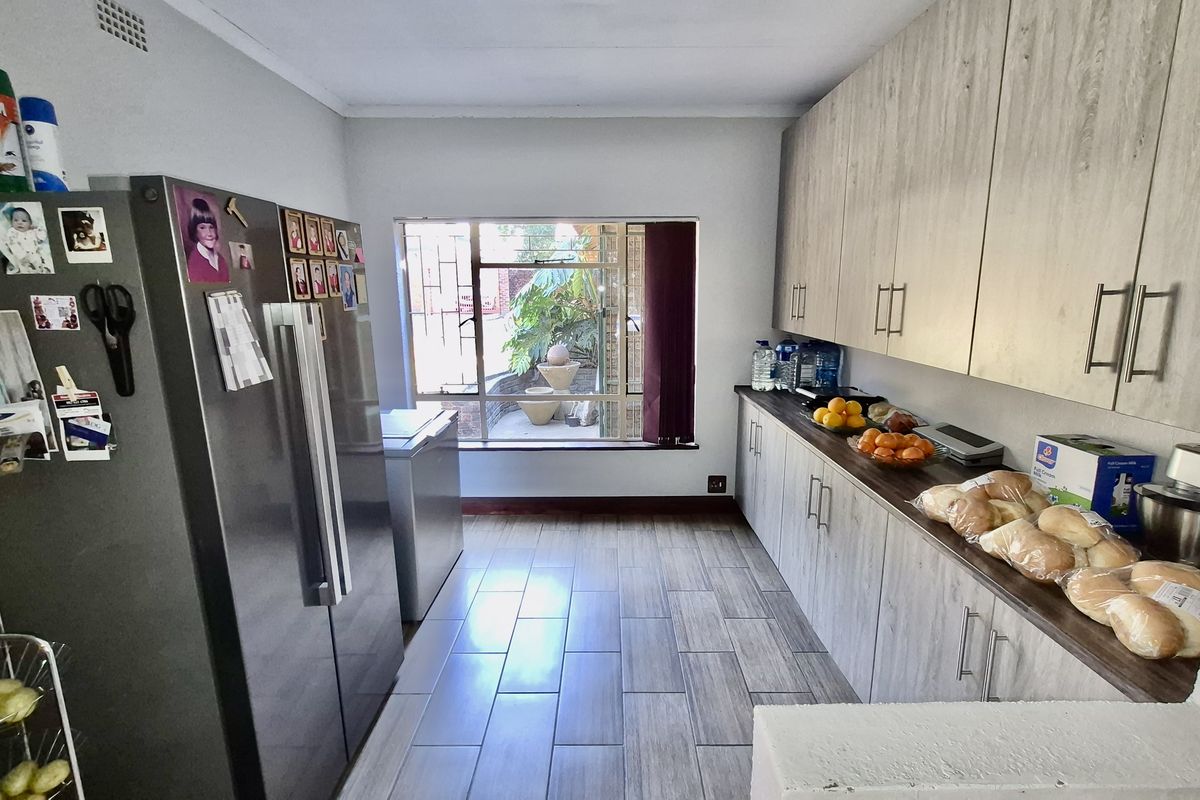 A functional kitchen featuring wood-look cabinetry, tiled flooring, and a large window providing natural light and a view of the outdoor area.