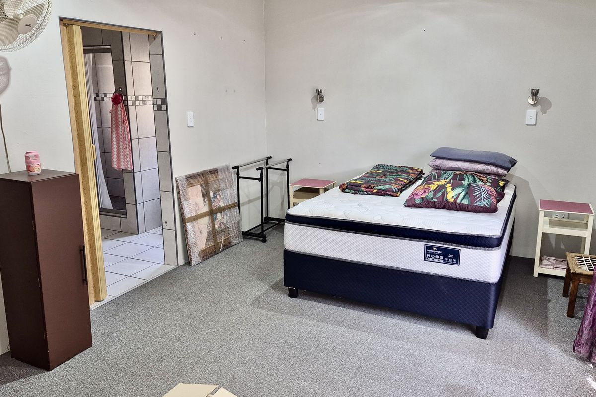 A functional bedroom featuring carpeted flooring, wall-mounted lighting, and direct access to an en-suite bathroom.