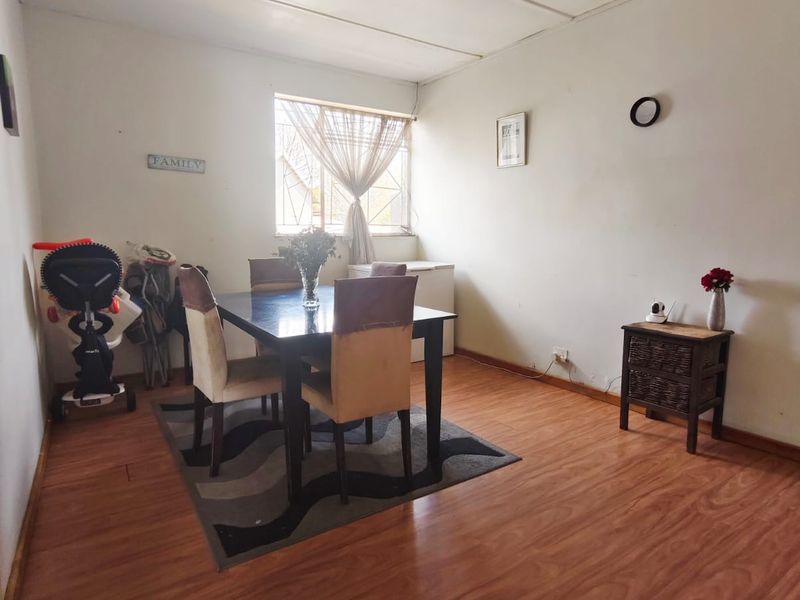 A dining room featuring laminate flooring and a window, providing a functional space that could benefit from cosmetic updates to the walls and ceiling.