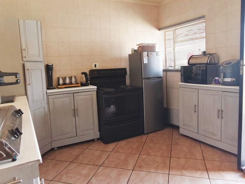 A functional kitchen featuring tiled flooring, tiled splashbacks, built-in cabinetry, and a freestanding stove with ample counter space.